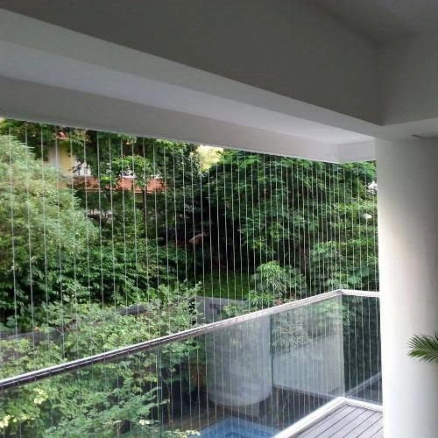 Invisible safety cables installed across a balcony overlooking greenery